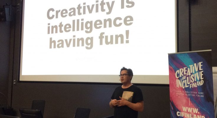 Panu Mäenpää puhumassa. Taustalla näkyy screen, jossa lukee "Creativity is intelligence having fun!"