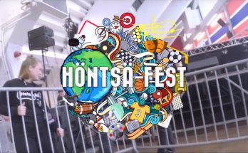 Kuvakaappaus Stadin ammattiopiston Höntsä-Fest-videosta, jossa näkyy tapahtuman logo ja taustalla nuoria asettelamassa keikan aitoja paikoilleen.