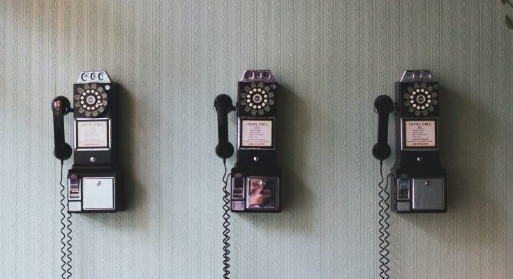 Kolme vanhaa puhelinta seinällä.